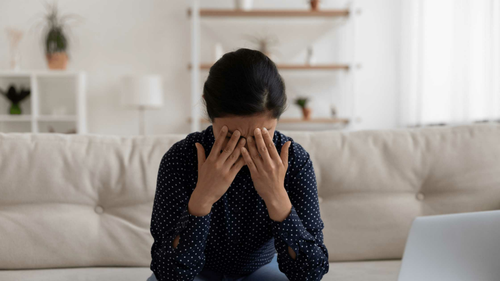 stressed woman sitting on couch looking at computer