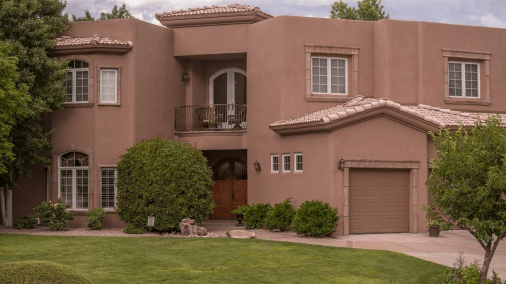 Large two story brown stucco house with green grass