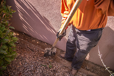 Tesuque Stucco contractor clearing debris from house with shovel