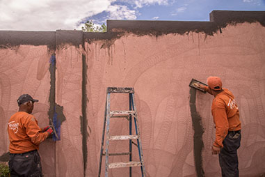 Two Tesuque Stucco contractors repairing old stucco fence
