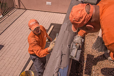 Two Tesuque Stucco contractors applying resin to protect the stucco