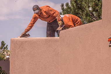 Man troweling stucco on top of roof